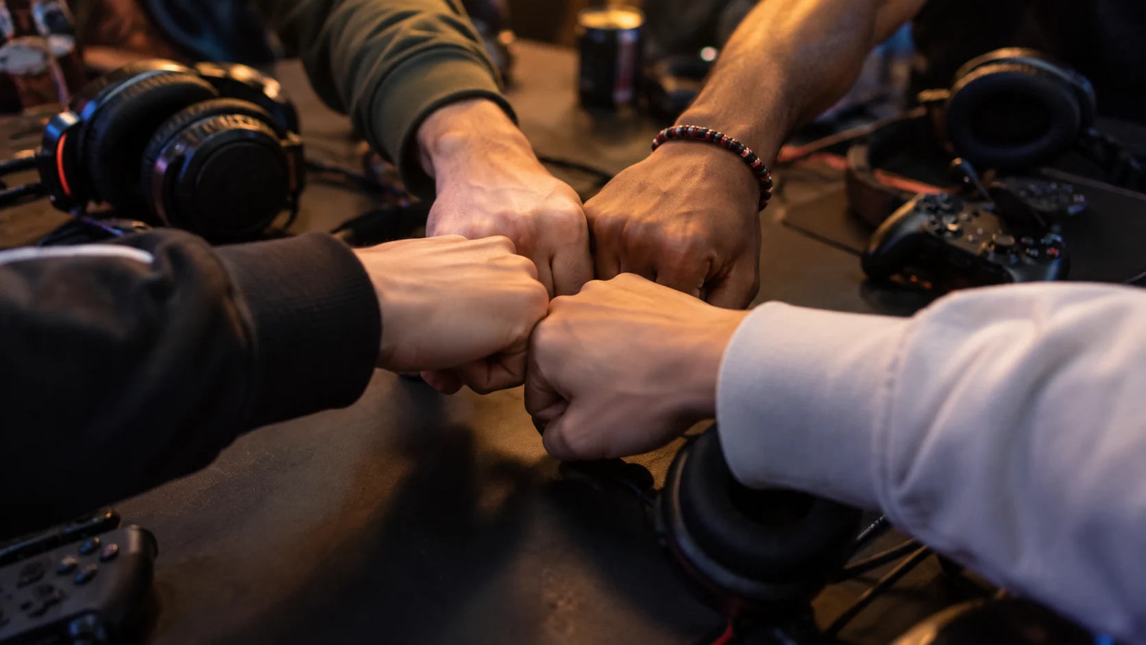 Teammates stack fists above a table with generic headsets and controllers.