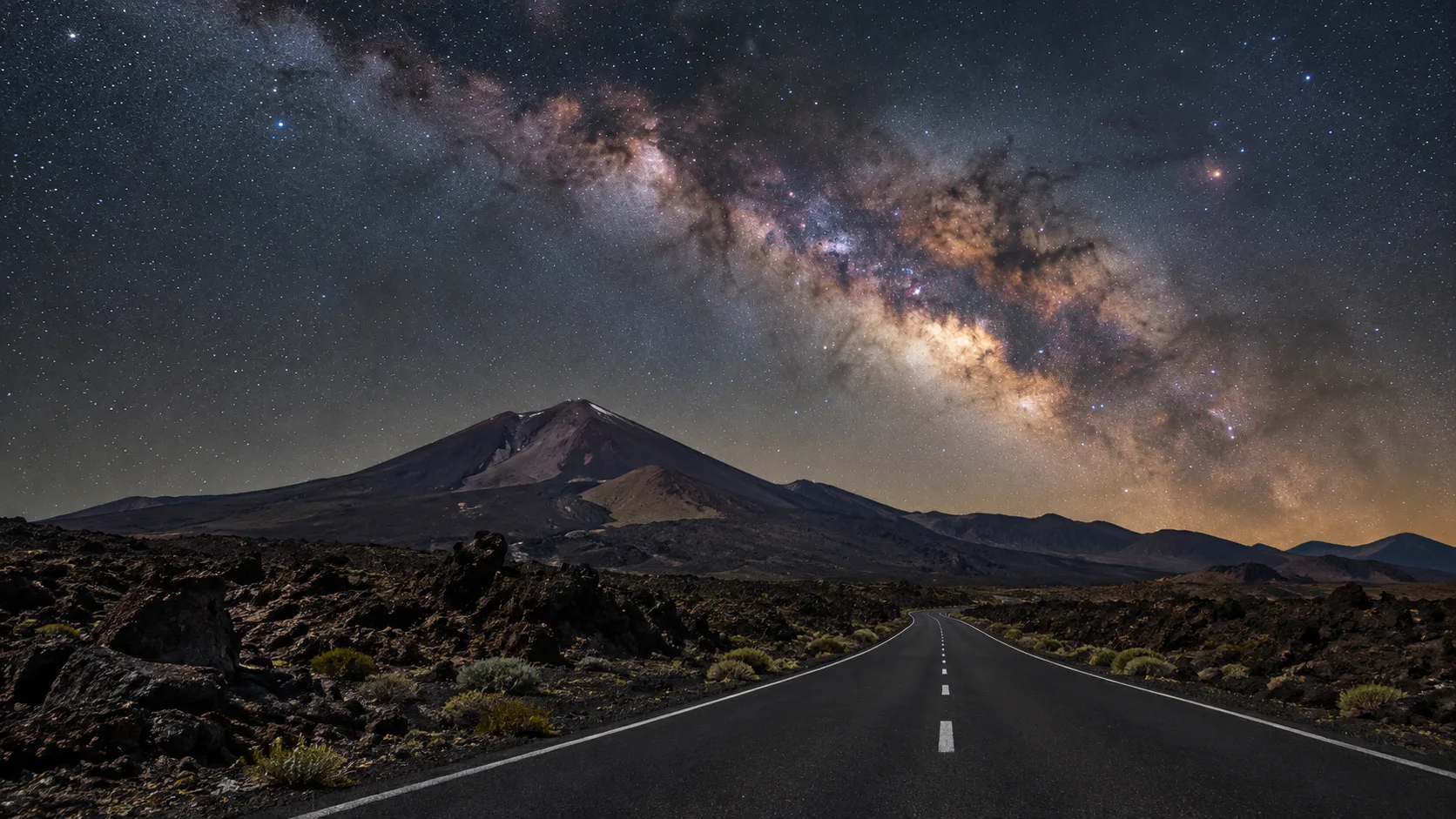 A quiet road crosses a volcanic landscape under the Milky Way.